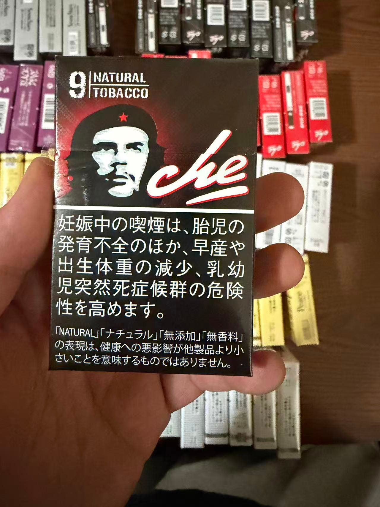 CHE LEADER BLACK 9mg pack held over a display of cigarette packs