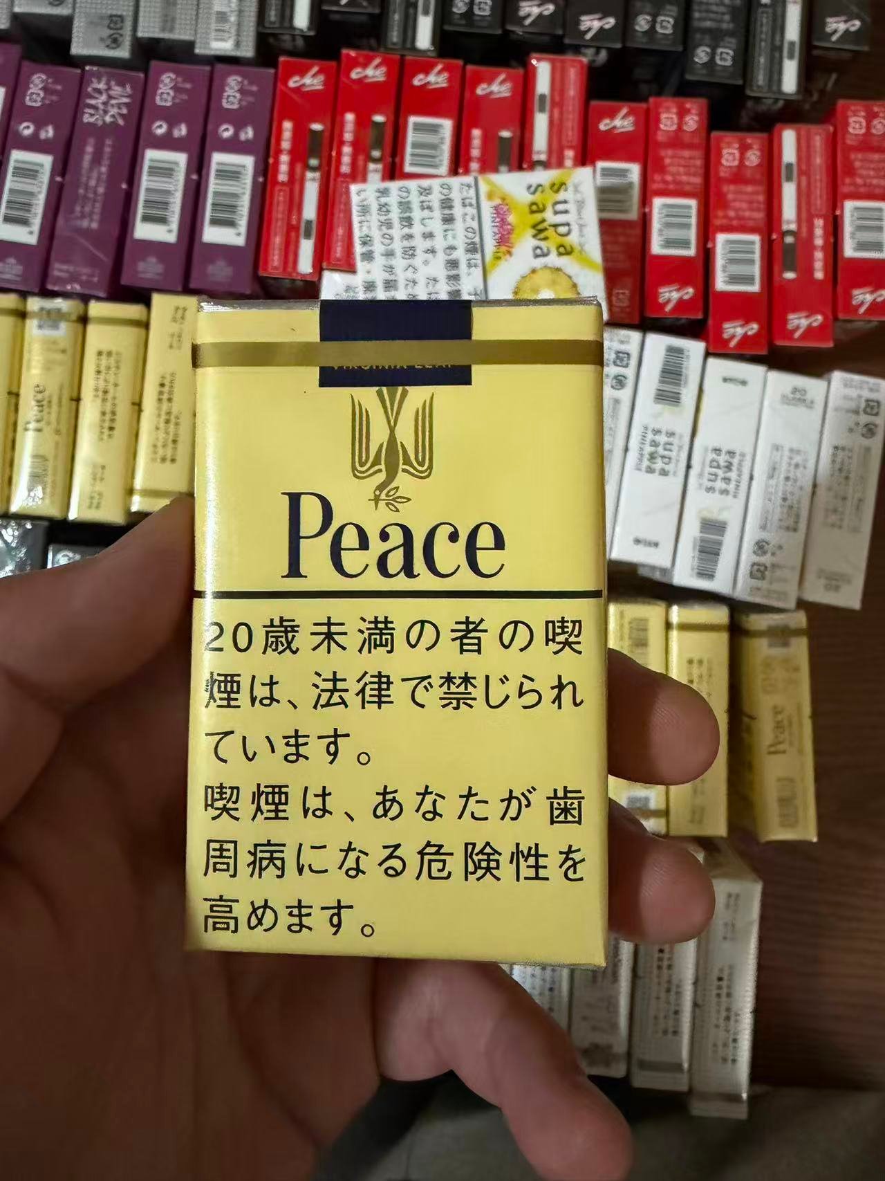Peace Yellow 21mg pack held over a display of cigarette packs