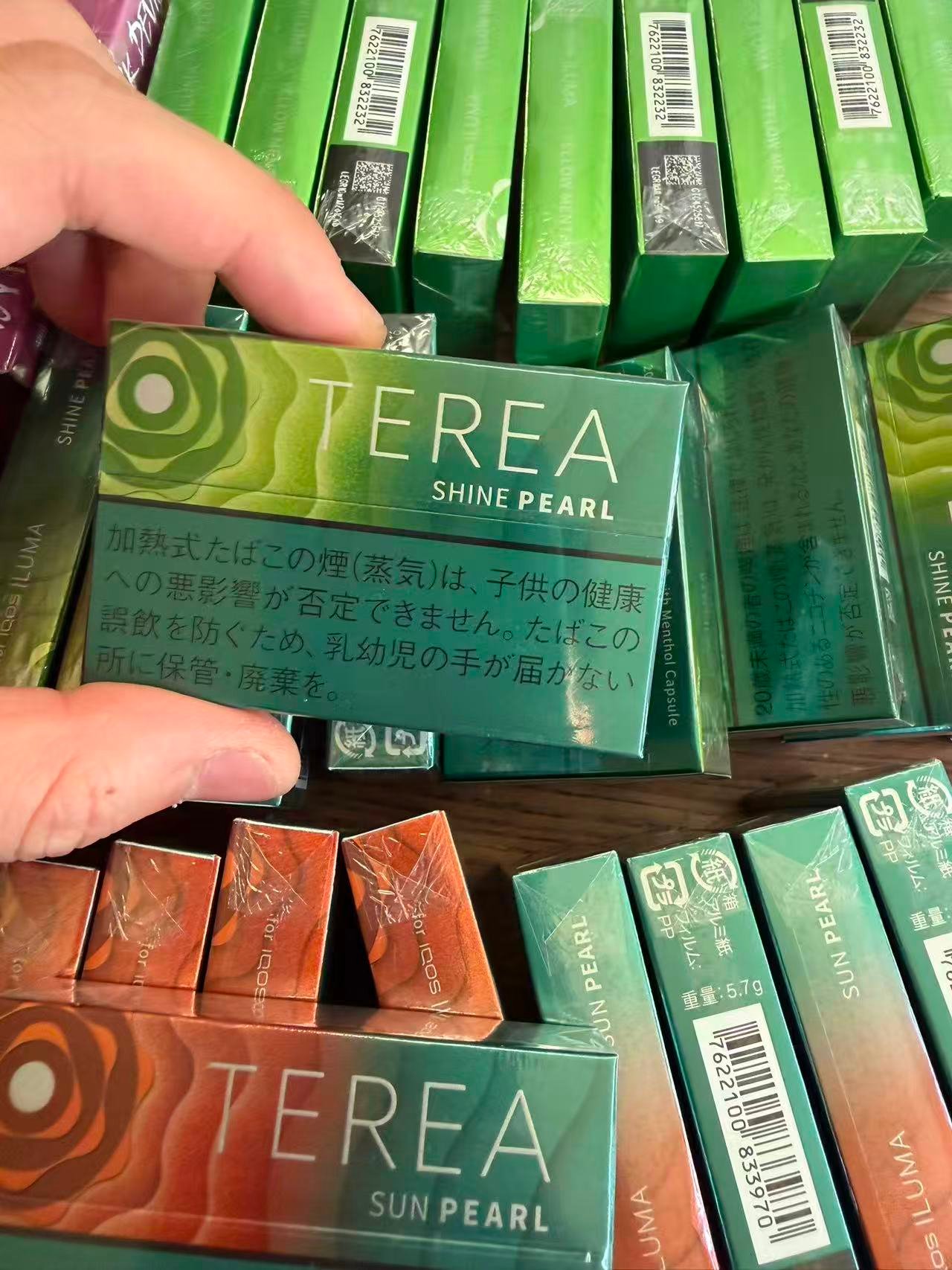 TEREA Shine Pearl pack held over a display of TEREA products