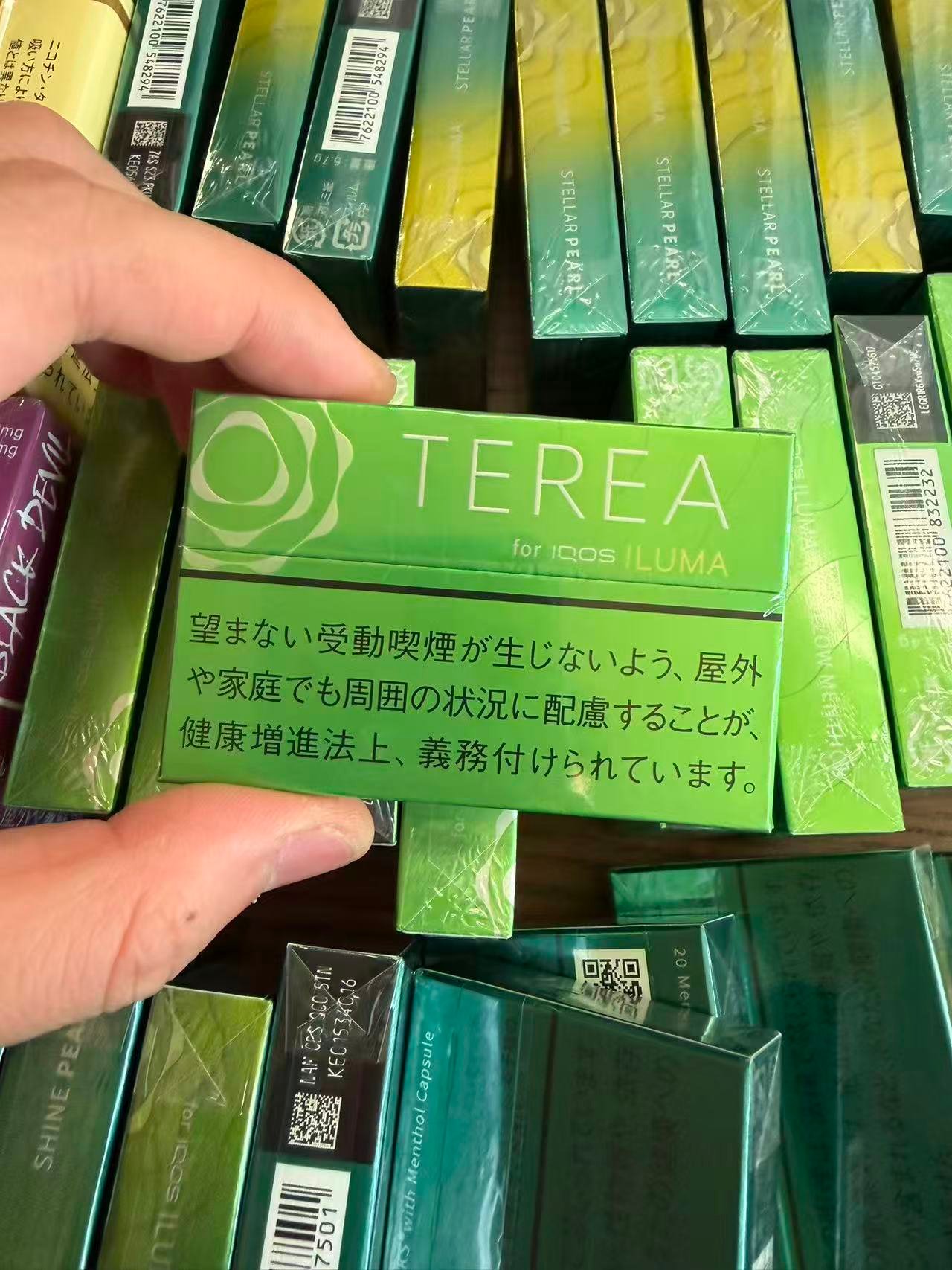 TEREA Yellow Menthol pack held over a display of TEREA products